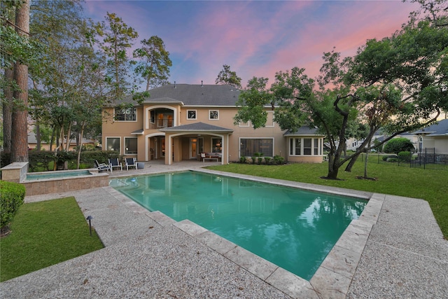 pool at dusk with a yard and a patio