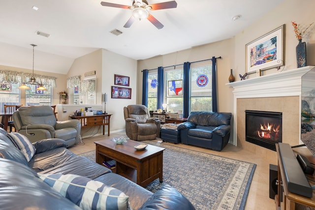 tiled living room with vaulted ceiling, ceiling fan with notable chandelier, a fireplace, and a wealth of natural light