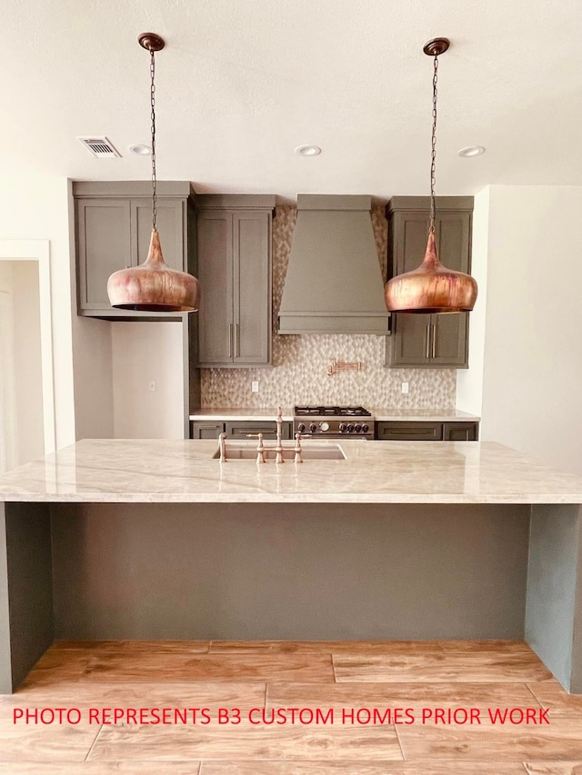 kitchen featuring pendant lighting, light wood-type flooring, high end stainless steel range, and custom exhaust hood