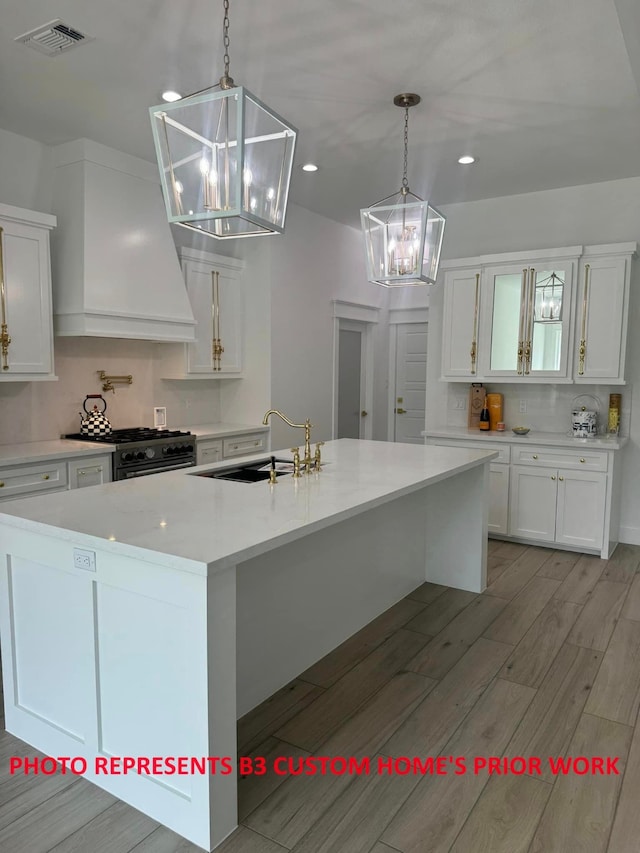 kitchen featuring sink, custom exhaust hood, white cabinetry, and hanging light fixtures