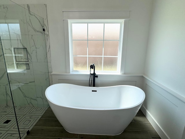 full bathroom featuring a freestanding tub, wood tiled floor, a marble finish shower, and wainscoting