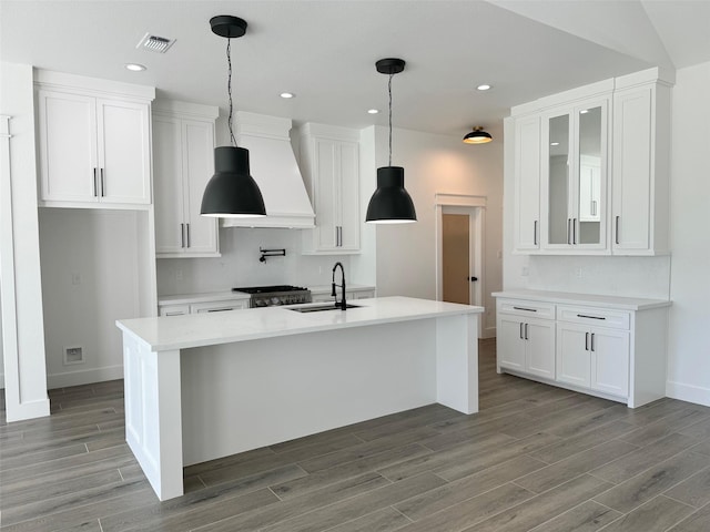 kitchen featuring custom exhaust hood, white cabinets, and a sink