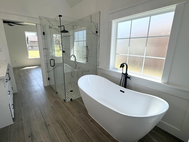 full bathroom featuring a marble finish shower, baseboards, a freestanding bath, vanity, and wood finish floors