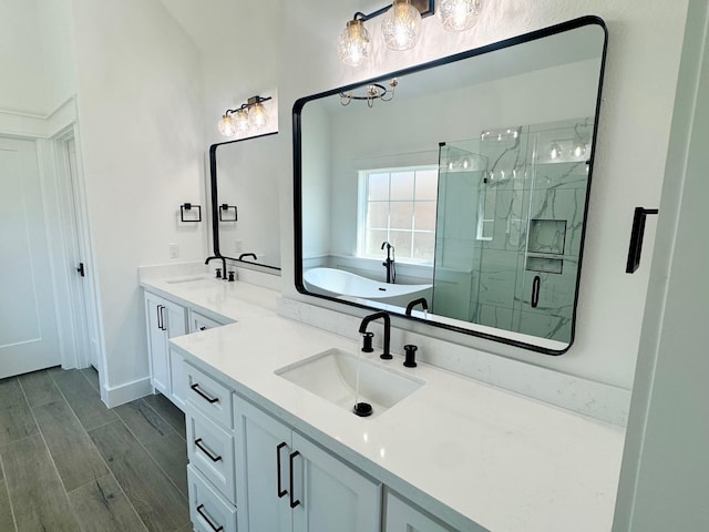 full bathroom featuring wood tiled floor, a garden tub, a sink, and a marble finish shower