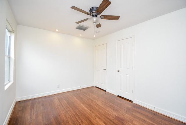 unfurnished bedroom with ceiling fan, multiple windows, and hardwood / wood-style floors