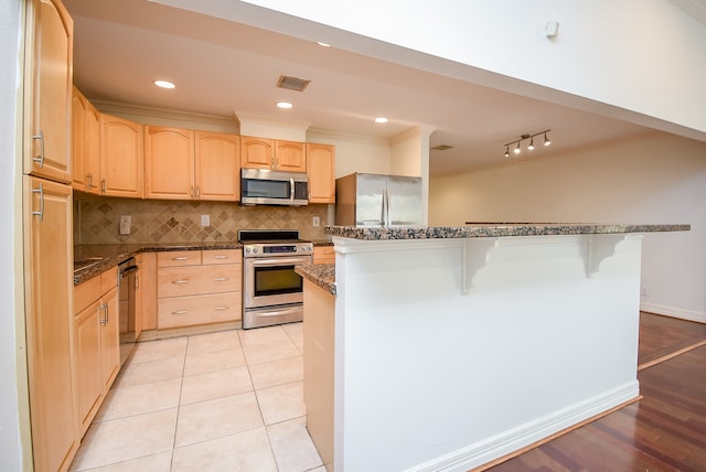 kitchen featuring light hardwood / wood-style floors, light brown cabinets, stainless steel appliances, and dark stone counters