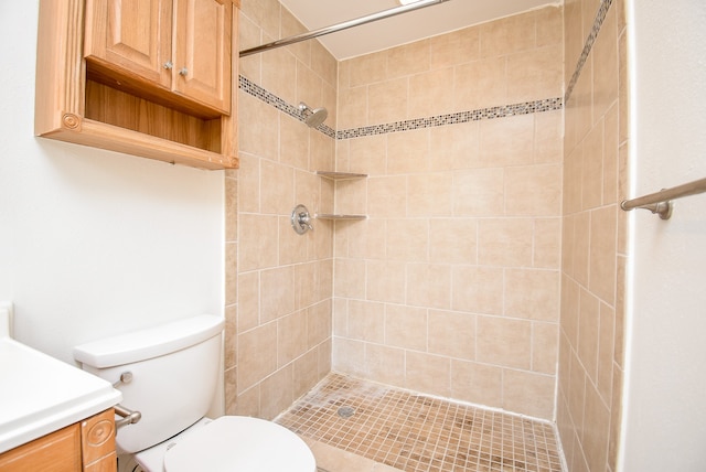 bathroom featuring a tile shower, toilet, and vanity