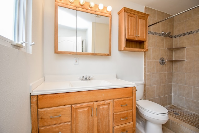 bathroom featuring toilet, vanity, and a tile shower