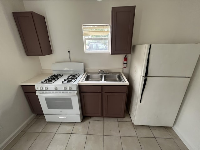 kitchen with white appliances, light tile patterned flooring, dark brown cabinetry, and sink