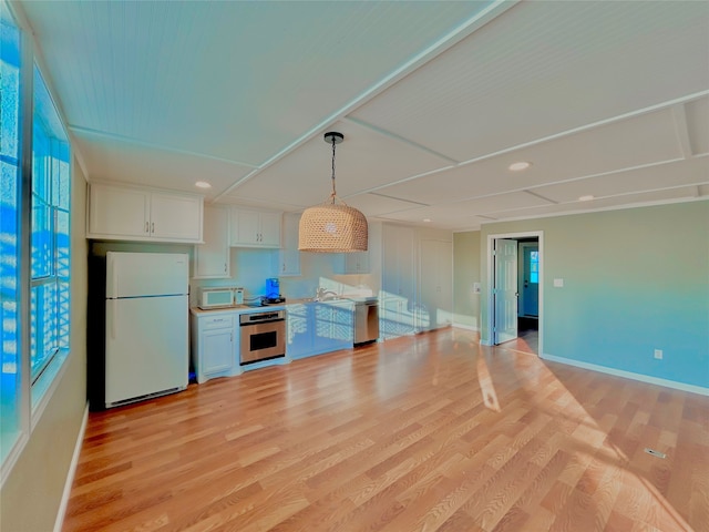 kitchen featuring appliances with stainless steel finishes, light hardwood / wood-style flooring, white cabinets, and hanging light fixtures