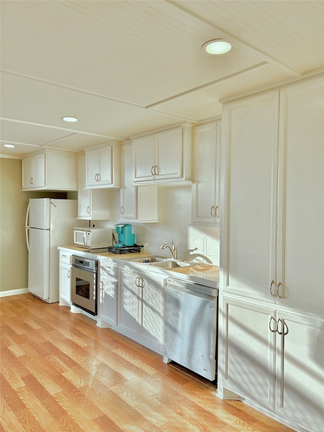 kitchen featuring sink, appliances with stainless steel finishes, light hardwood / wood-style flooring, and white cabinets