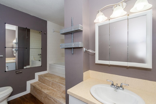 full bathroom featuring tiled shower / bath, hardwood / wood-style floors, vanity, and toilet