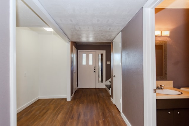 hallway featuring a textured ceiling, dark wood-type flooring, and sink