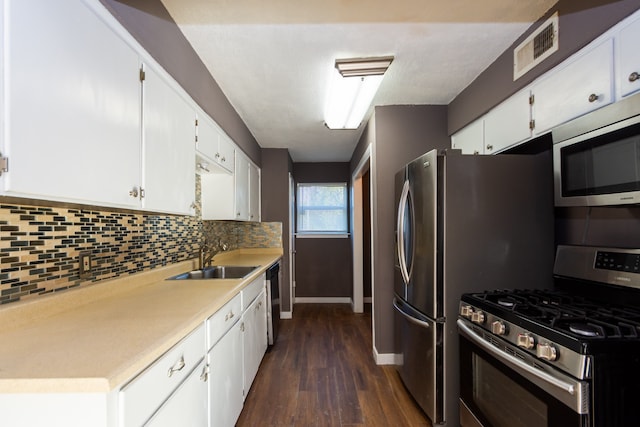 kitchen featuring appliances with stainless steel finishes, white cabinetry, dark wood-type flooring, and sink