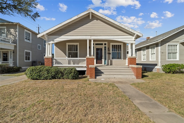 view of front of house with cooling unit, a front lawn, and covered porch