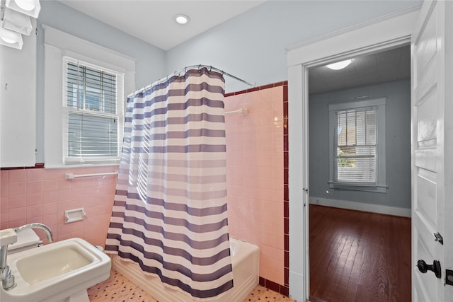 bathroom with wood-type flooring, sink, shower / tub combo, and tile walls