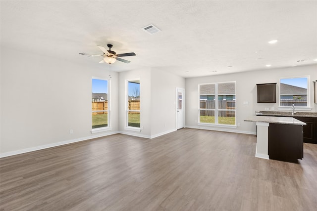 unfurnished living room featuring a wealth of natural light, hardwood / wood-style floors, ceiling fan, and sink