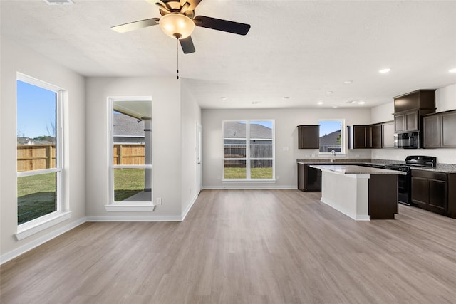 kitchen with dark brown cabinetry, sink, light hardwood / wood-style floors, a kitchen island, and stainless steel range with electric cooktop