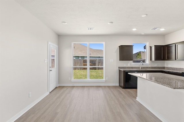 kitchen featuring light stone countertops, dishwasher, sink, light hardwood / wood-style floors, and dark brown cabinets