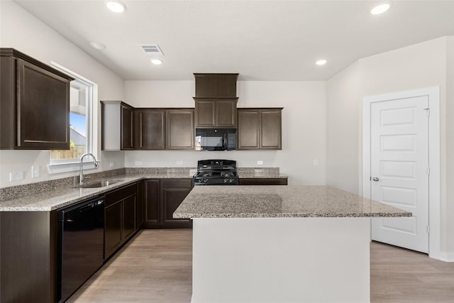 kitchen featuring light stone counters, sink, black appliances, light hardwood / wood-style flooring, and a kitchen island