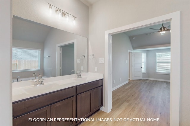 bathroom with hardwood / wood-style flooring, ceiling fan, lofted ceiling, a bath, and vanity