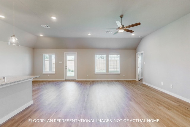 unfurnished living room featuring lofted ceiling, light wood-type flooring, a wealth of natural light, and ceiling fan