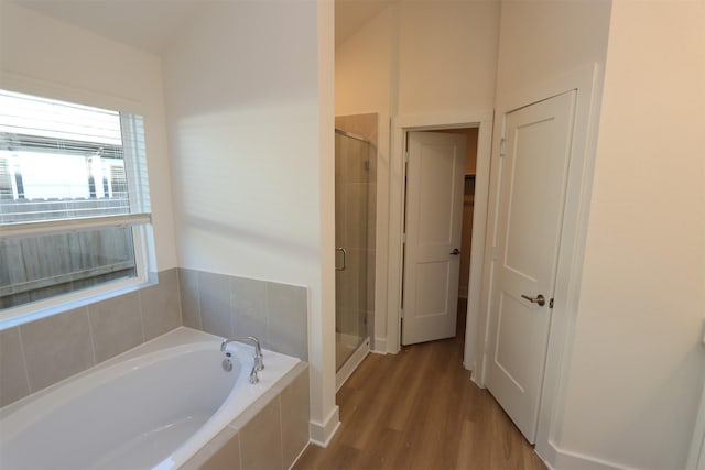 bathroom with a stall shower, wood finished floors, and a bath