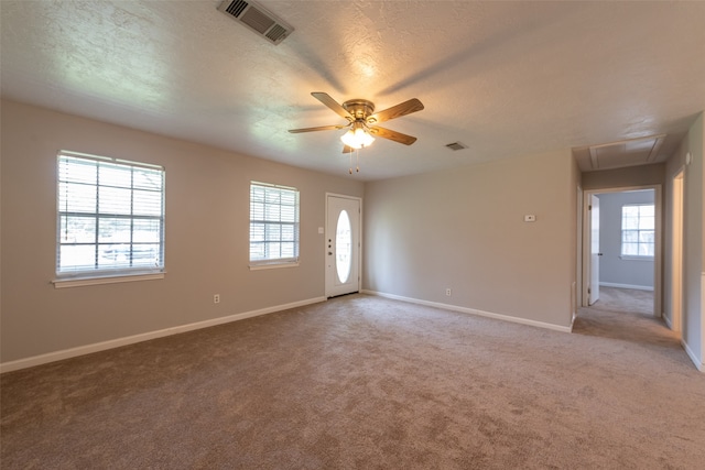 carpeted spare room featuring ceiling fan, a textured ceiling, and plenty of natural light