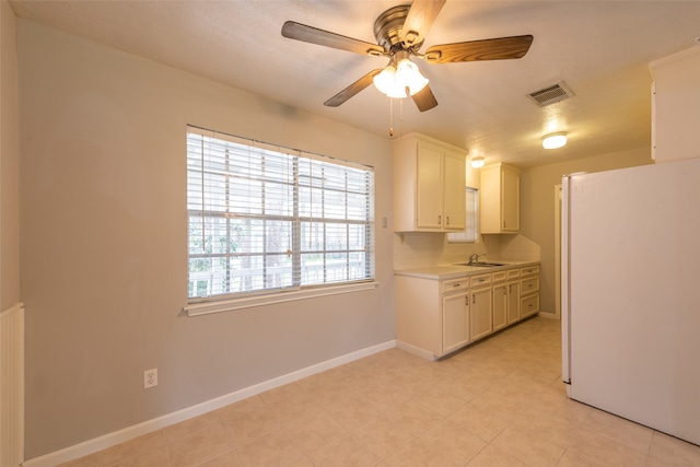 kitchen with ceiling fan, light tile patterned floors, white cabinetry, sink, and white refrigerator