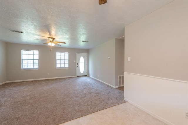 spare room featuring light carpet, a textured ceiling, and ceiling fan