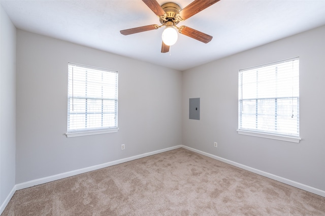 carpeted empty room with ceiling fan, a healthy amount of sunlight, and electric panel