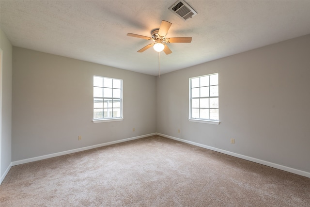 empty room with a textured ceiling, ceiling fan, carpet flooring, and a wealth of natural light