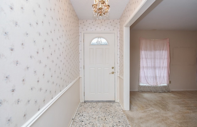 foyer entrance featuring light carpet, a textured ceiling, and a chandelier