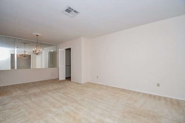 carpeted spare room featuring an inviting chandelier