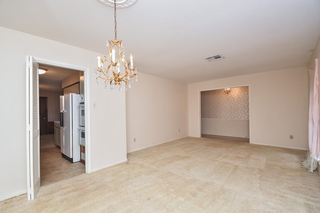 carpeted spare room with a chandelier