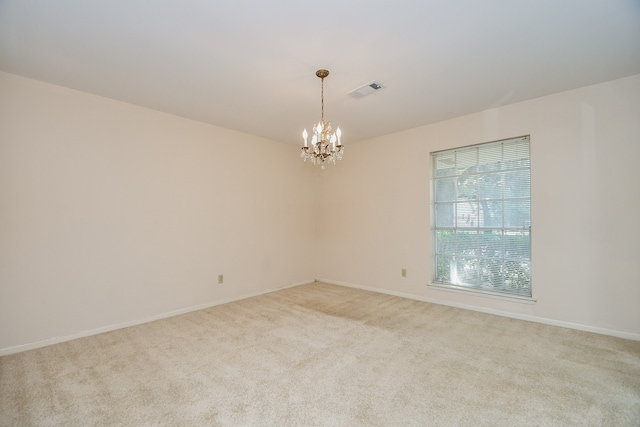 carpeted spare room with an inviting chandelier