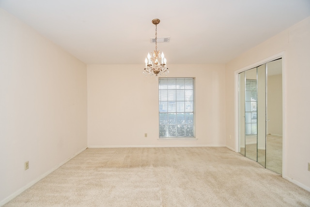 carpeted empty room with an inviting chandelier