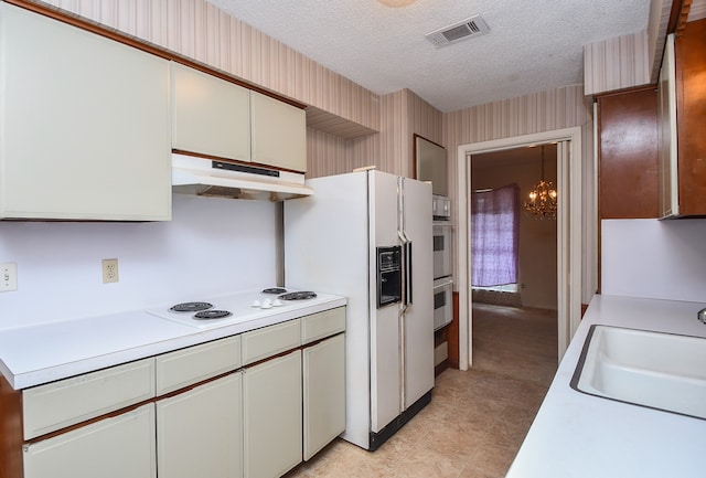 kitchen with white appliances, a textured ceiling, and sink