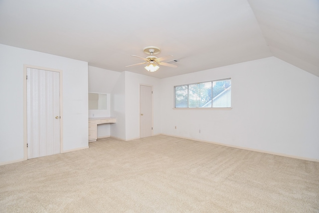 bonus room with built in desk, ceiling fan, lofted ceiling, and light colored carpet