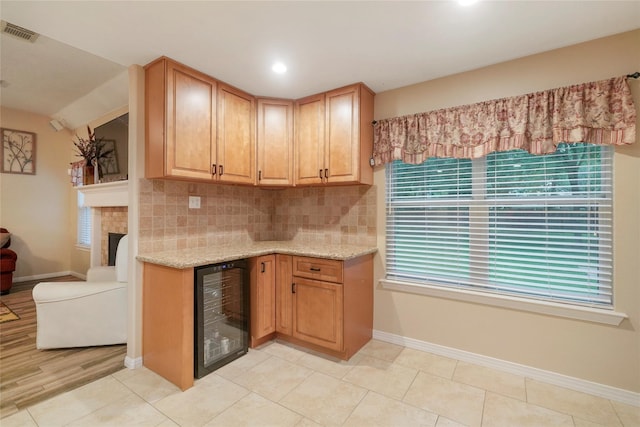 kitchen with decorative backsplash, light stone counters, beverage cooler, and light tile patterned floors