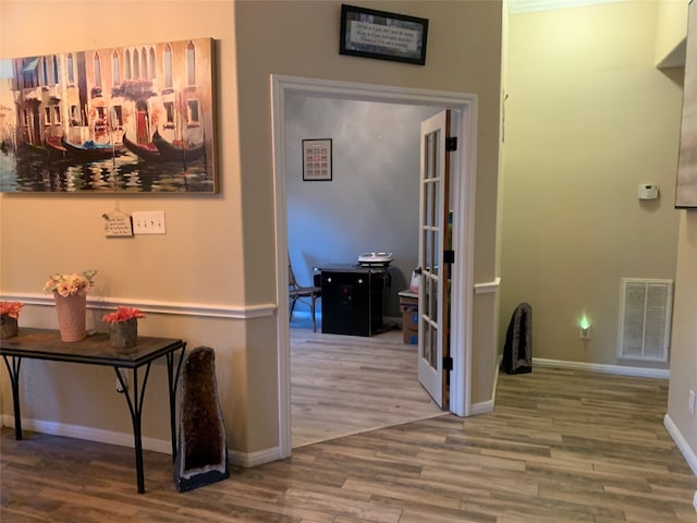 hallway with french doors, crown molding, and hardwood / wood-style flooring