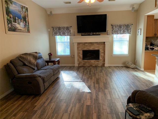 living room featuring a wealth of natural light, a brick fireplace, and dark hardwood / wood-style floors