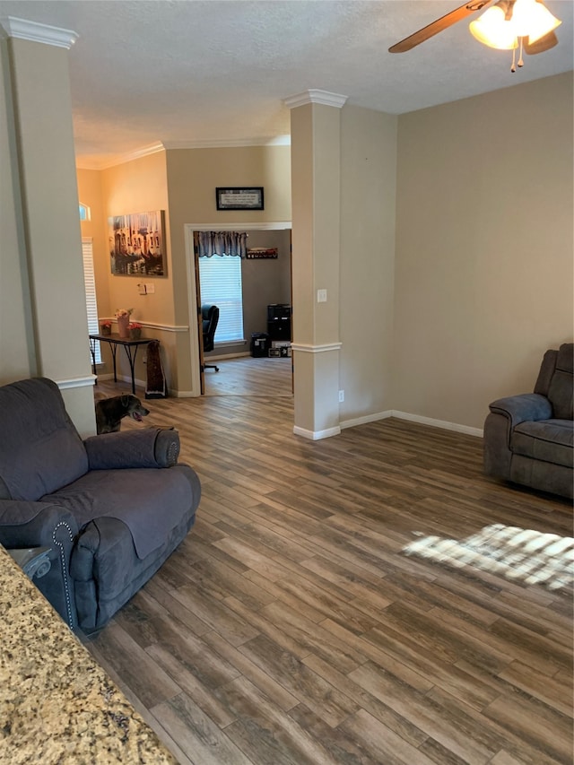 living room with dark wood-type flooring, ceiling fan, ornamental molding, and a textured ceiling