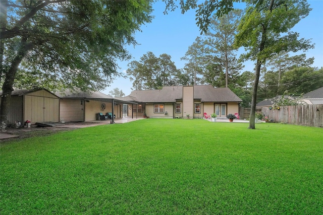 back of house with a patio area, a lawn, and a storage shed