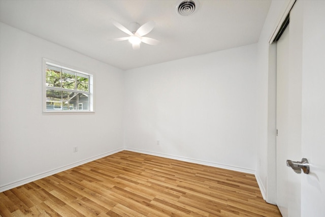 empty room featuring light wood-style flooring, a ceiling fan, visible vents, and baseboards