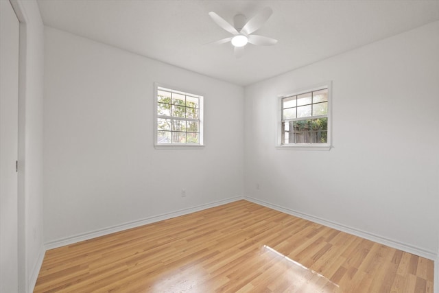 empty room featuring baseboards, ceiling fan, a wealth of natural light, and light wood-style floors