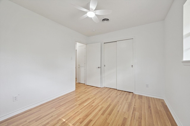 unfurnished bedroom with ceiling fan, wood finished floors, visible vents, baseboards, and a closet