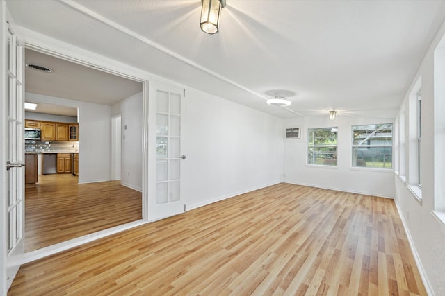 unfurnished room with light wood-type flooring, visible vents, and baseboards