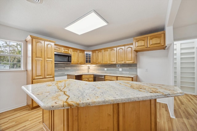 kitchen with appliances with stainless steel finishes, light wood-type flooring, light stone counters, and tasteful backsplash