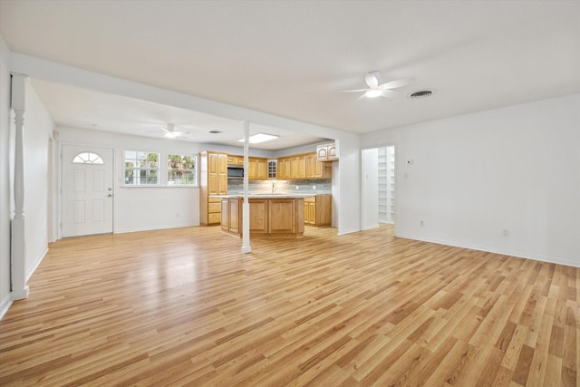 unfurnished living room with a ceiling fan, visible vents, light wood-style flooring, and baseboards